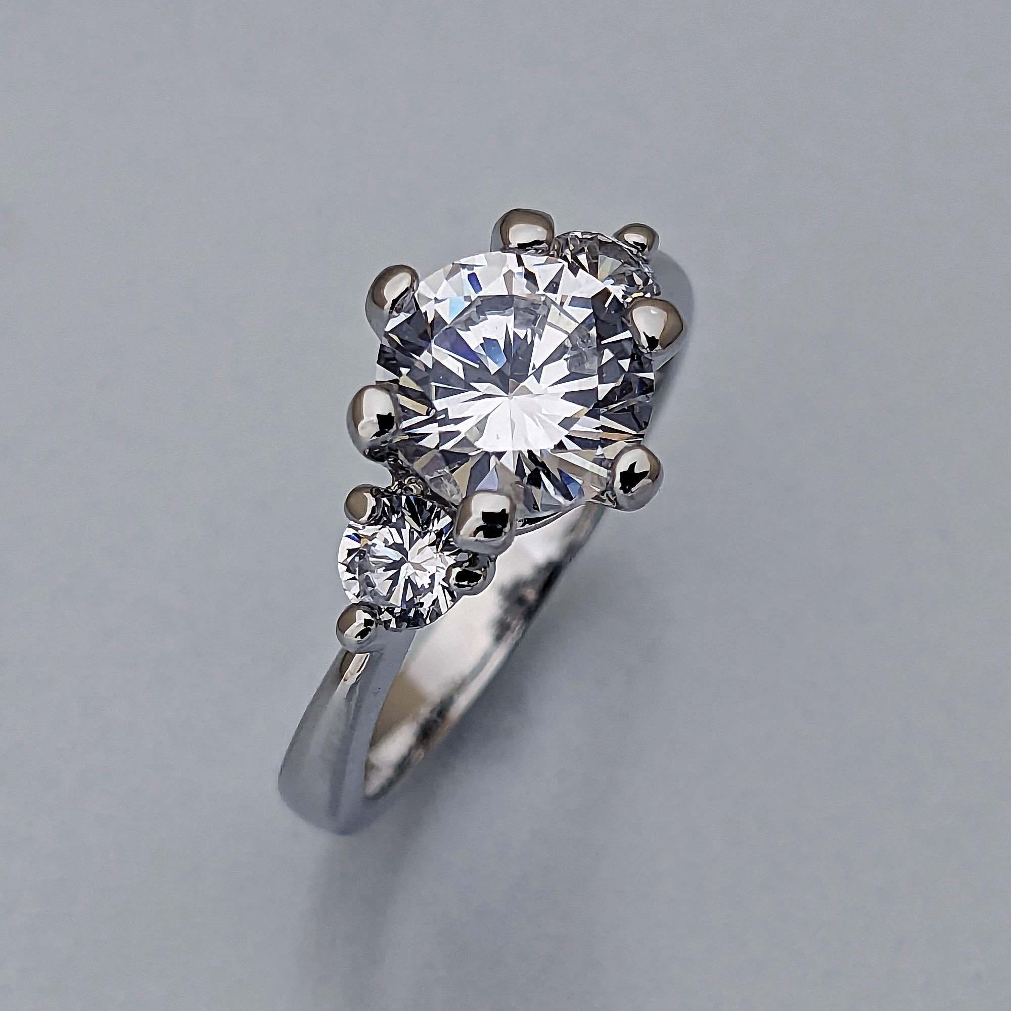 ２カラットダイヤモンドと両側にもダイヤモンドを留めたスリーストーンの婚約指輪